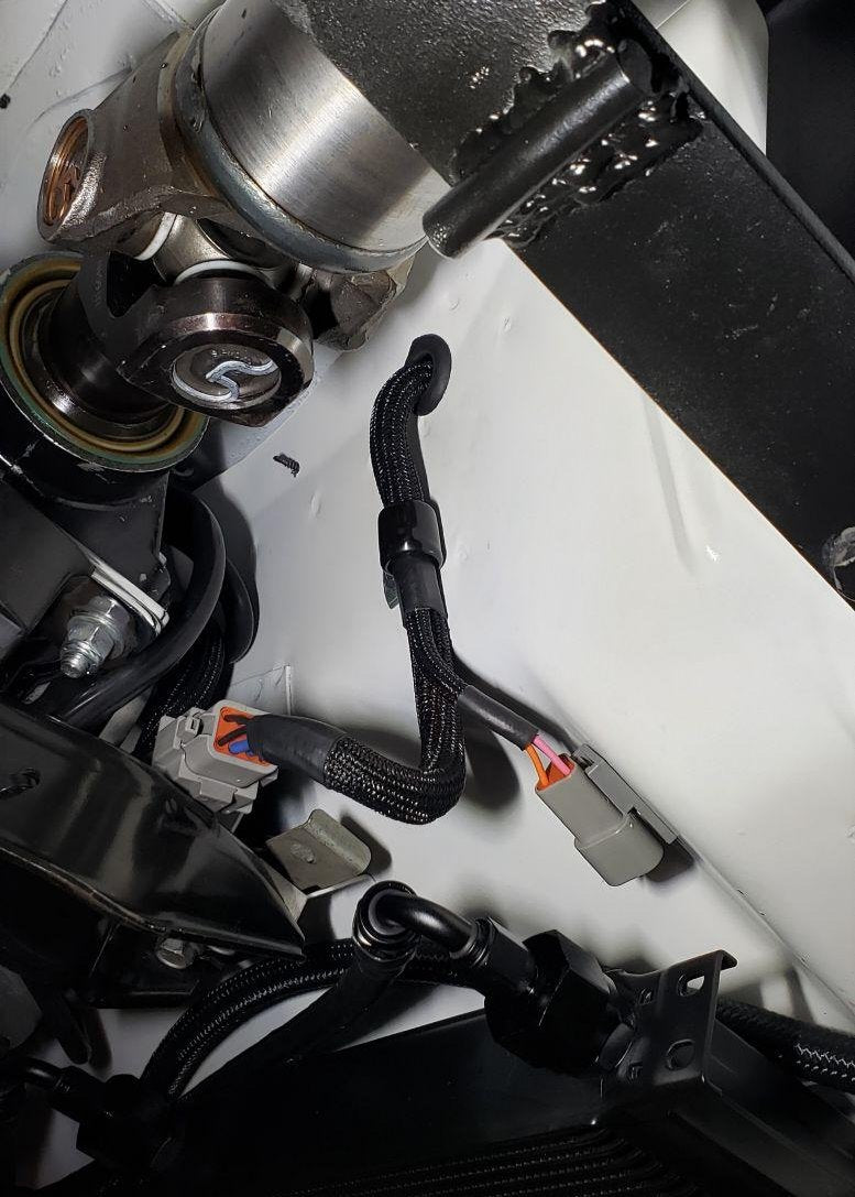 Showing a harness branch point of a completed harness, installed, from underneath the car, sheathed in TechFlex F6 Wrap. Assembled by Nocturnal Automotive / Auto.